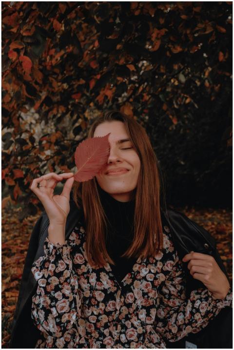 Woman in floral dress smiling with leaf over eye i