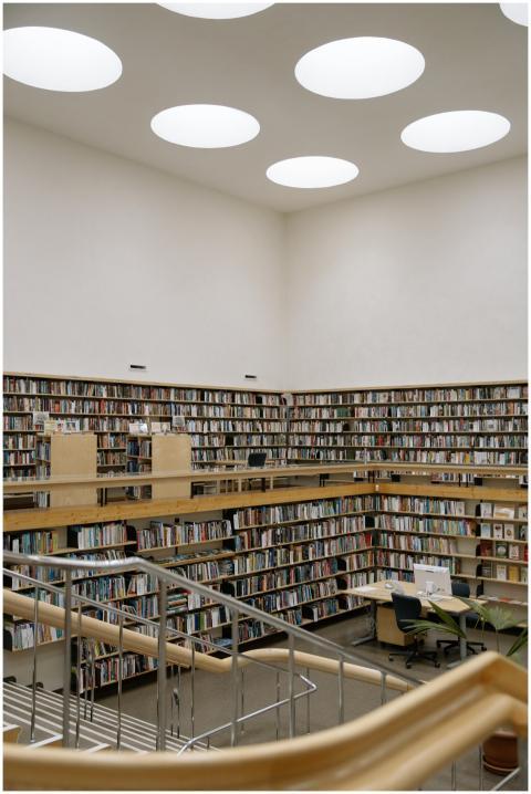 A spacious modern library with high bookshelves, s