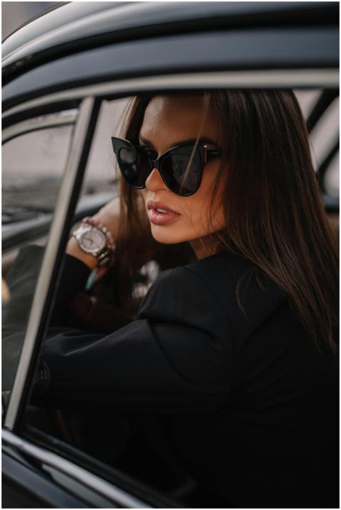 Chic woman sitting in a car, wearing sunglasses an