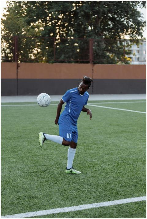 A young male soccer player in blue jersey practici