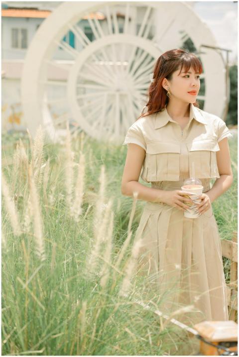 A young woman stands in a grassy field holding a c