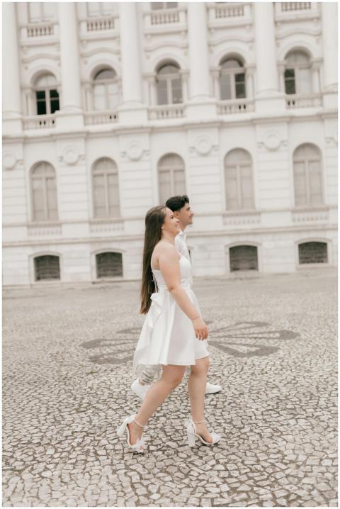 A couple gracefully walking past a historic white
