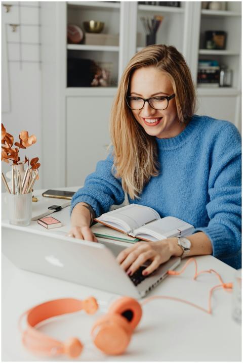 A cheerful woman in a blue sweater working remotel