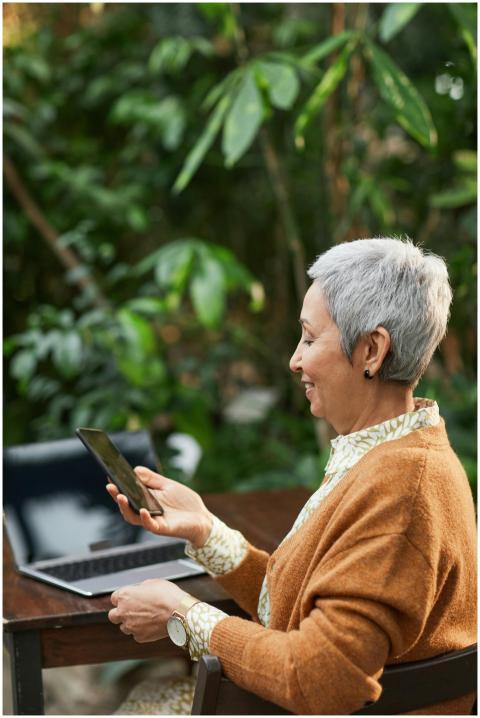 Elderly woman smiling while using a smartphone at