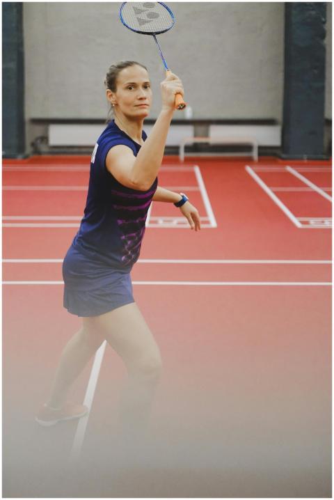 A woman plays badminton on an indoor court, showca