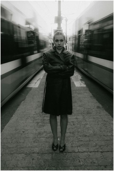 Woman stands between moving trams in a dynamic bla