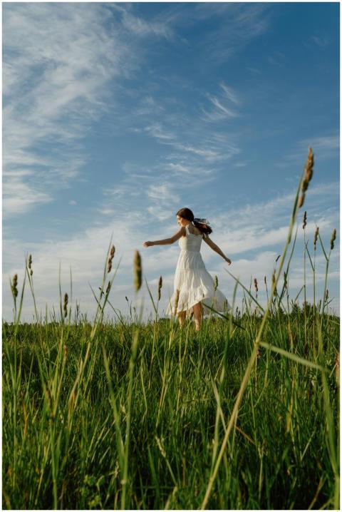 A woman in a white dress joyfully dances in a sunl