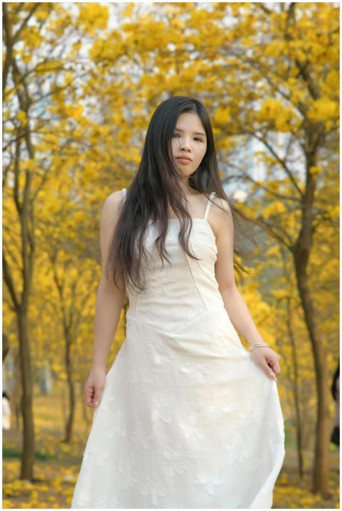 A woman in a white dress stands elegantly among go