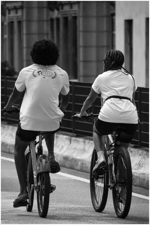 Two adults cycling side by side in São Paulo, repr