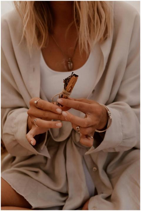 A woman holds a Palo Santo stick, capturing a mome