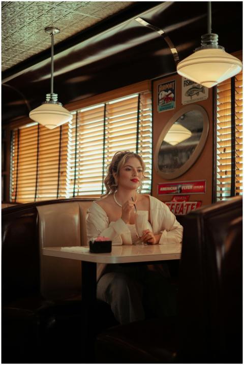 Blonde woman sits in a cozy vintage diner, enjoyin
