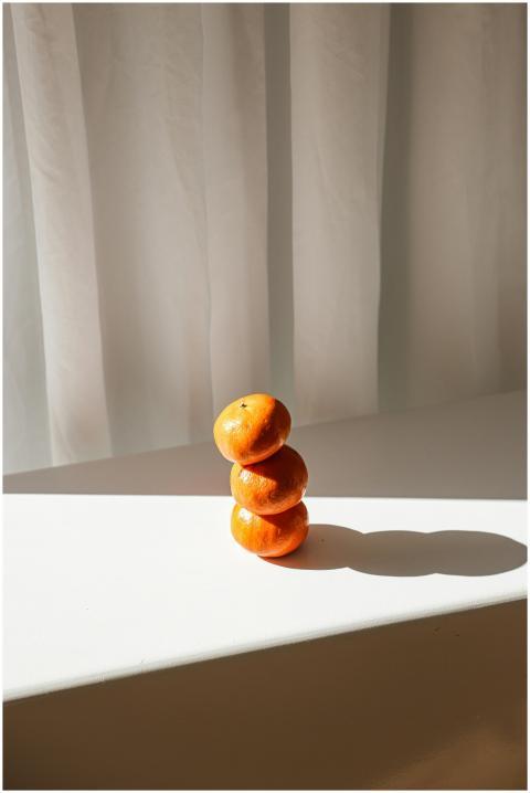A minimalist stack of oranges illuminated by natur