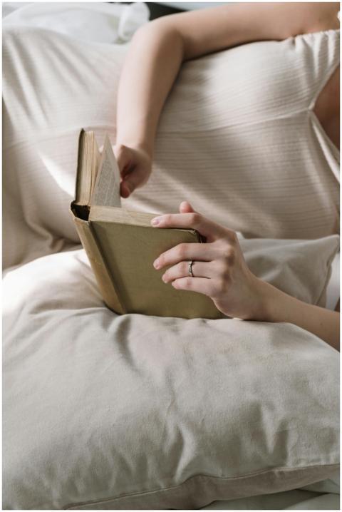 Woman relaxing on pillows, reading a hardcover boo