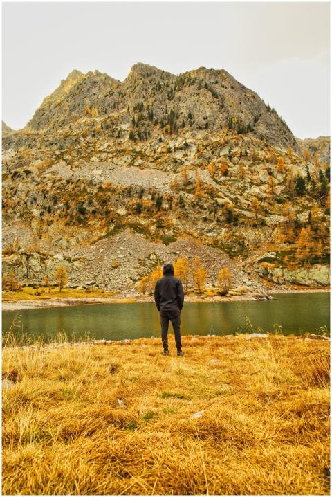 A person stands by a lake, gazing at the majestic