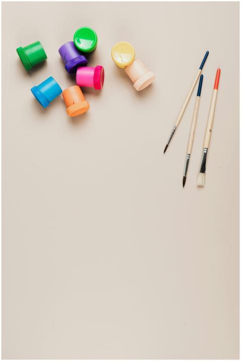 Top-down view of colorful paint jars and brushes o