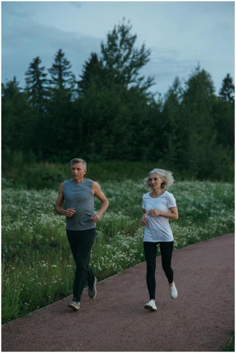 Elderly couple jogging on a serene park path surro