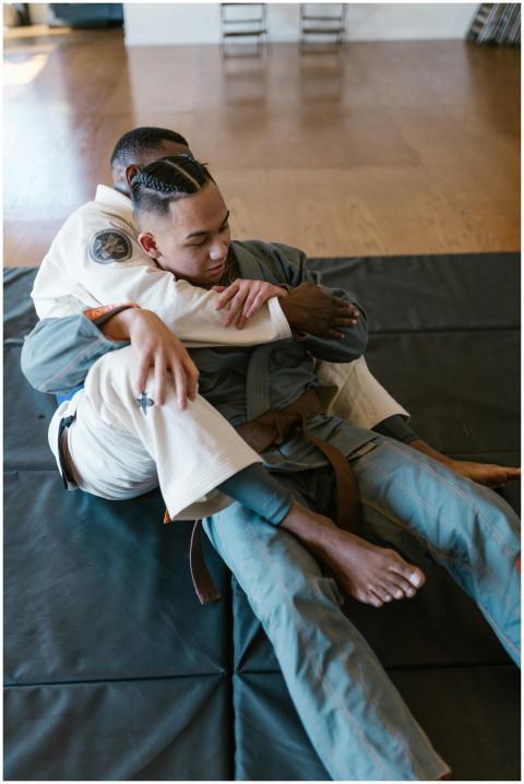Two adults practicing grappling techniques in an i