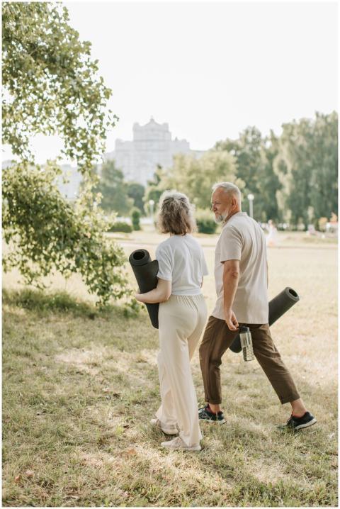 Elderly couple walking in park carrying yoga mats