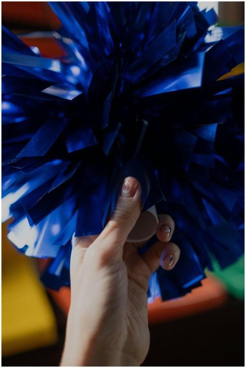 Close-up of a hand holding a vibrant blue pom-pom,