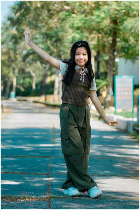 Happy young girl posing playfully in a sunlit park