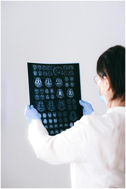A radiologist holds and examines a detailed MRI sc