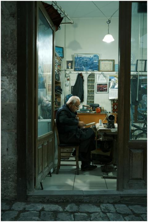 A senior tailor works diligently in a vintage-styl