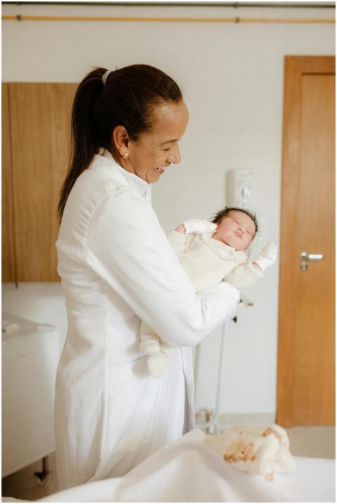 Female doctor happily holding a newborn baby in a