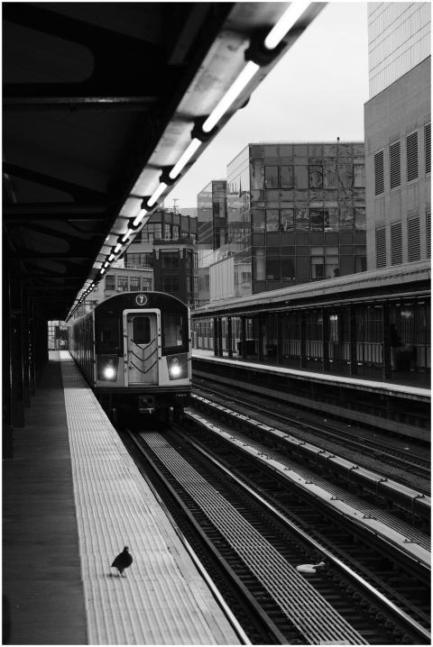 A black and white photo of an NYC subway train arr