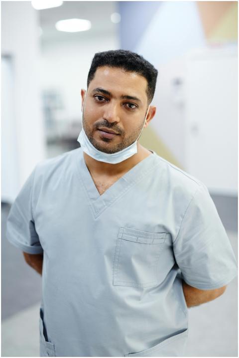 A healthcare worker in blue scrubs standing indoor