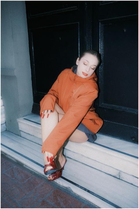 Stylish woman sitting on steps wearing an orange c