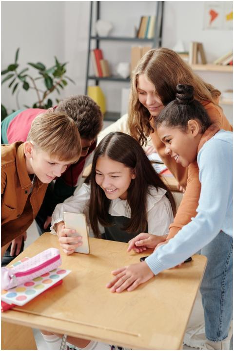 Happy students gathered around a smartphone in a l
