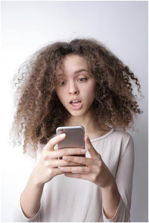 A young woman with curly hair looks surprised whil