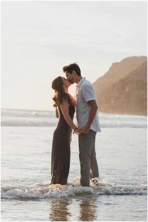 A couple shares an intimate kiss on a sunlit beach
