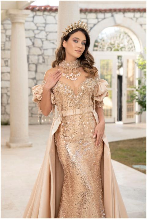 Stunning woman in a shimmering gold gown posing at