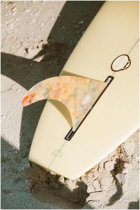 Surfboard fin resting on sand, capturing the essen