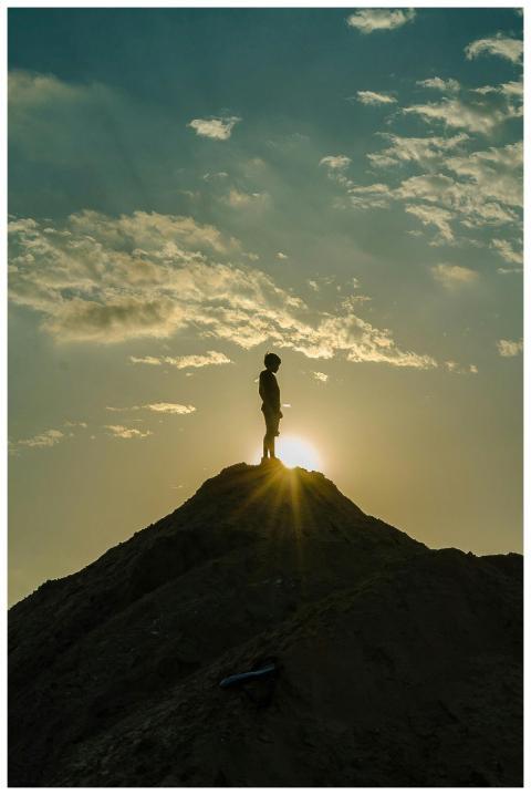 A silhouette of a person standing on a peak during