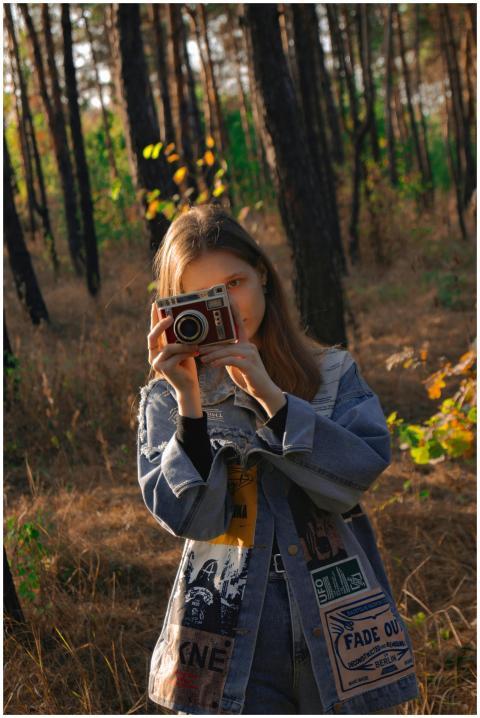 A girl in a denim jacket captures moments in a fal