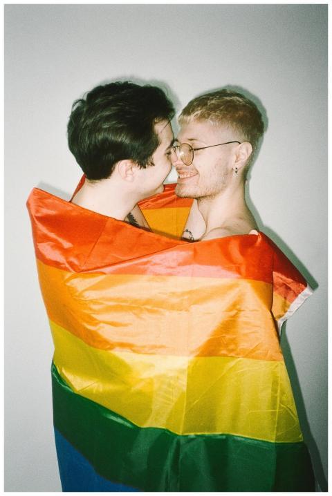 Happy LGBTQ couple wrapped in a vibrant pride flag