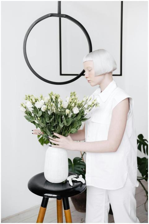 A woman with short hair arranging flowers in a whi
