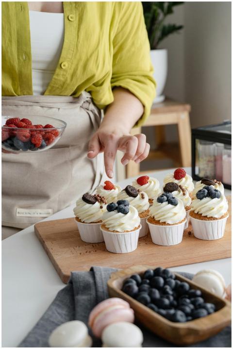 Close-up of cupcakes being decorated with fresh ra