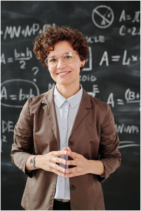 Teacher standing by a blackboard with algebra equa