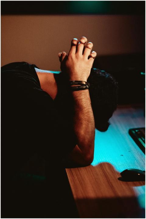 Man showing stress and exhaustion, leaning on a de