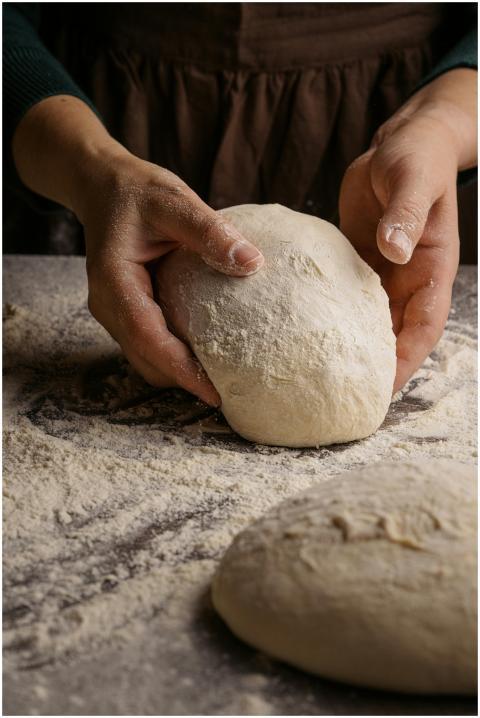 A baker's hands kneading fresh dough on a floured