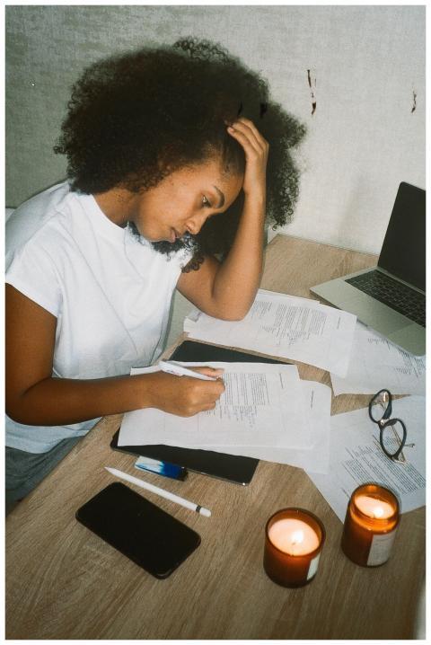 A stressed young woman works from home with candle