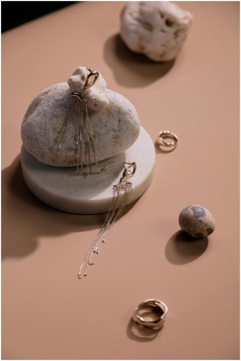 Chic earrings and rings artfully arranged on stone