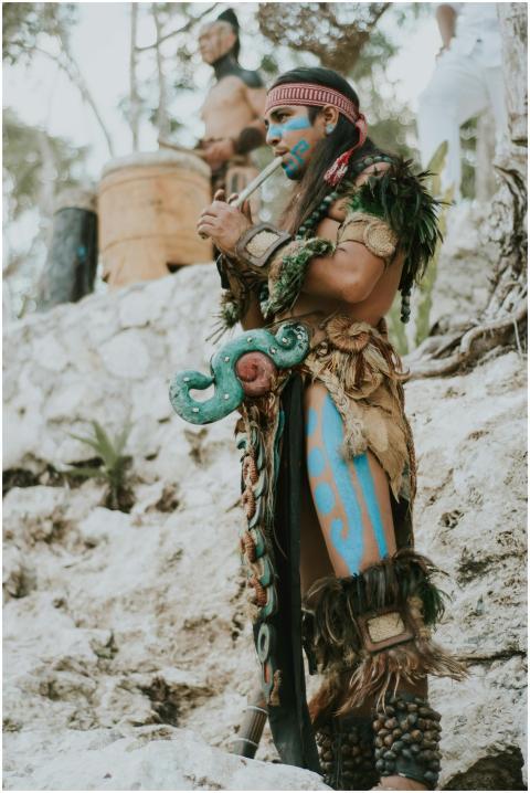 A Mayan musician in traditional attire plays the f