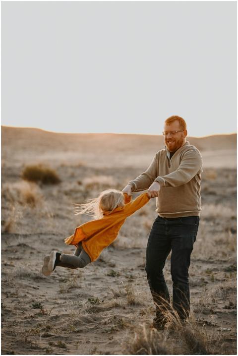 A joyful father spins his daughter in a sunny dese