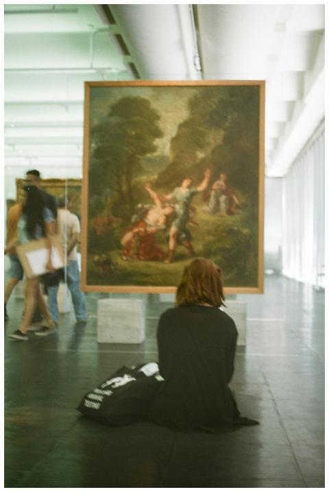 A woman observes an artwork in a museum, embodying