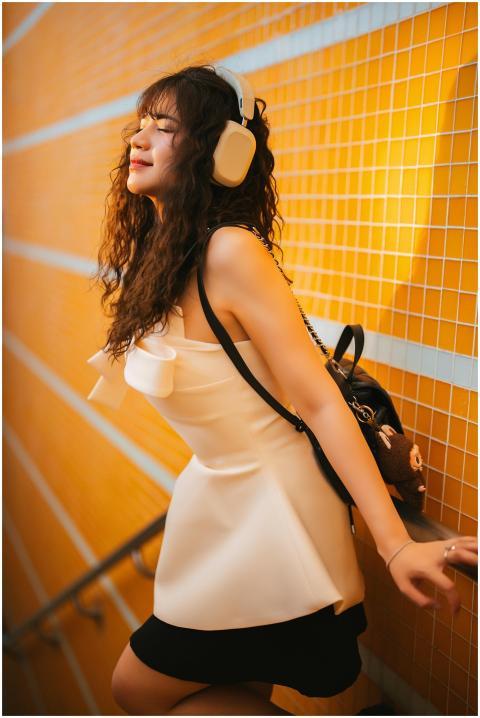Woman in white dress with headphones enjoying musi