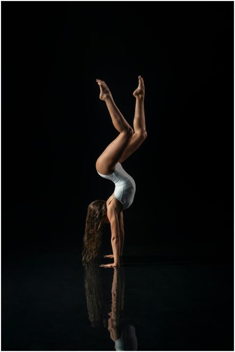 A woman performs a graceful handstand on a reflect